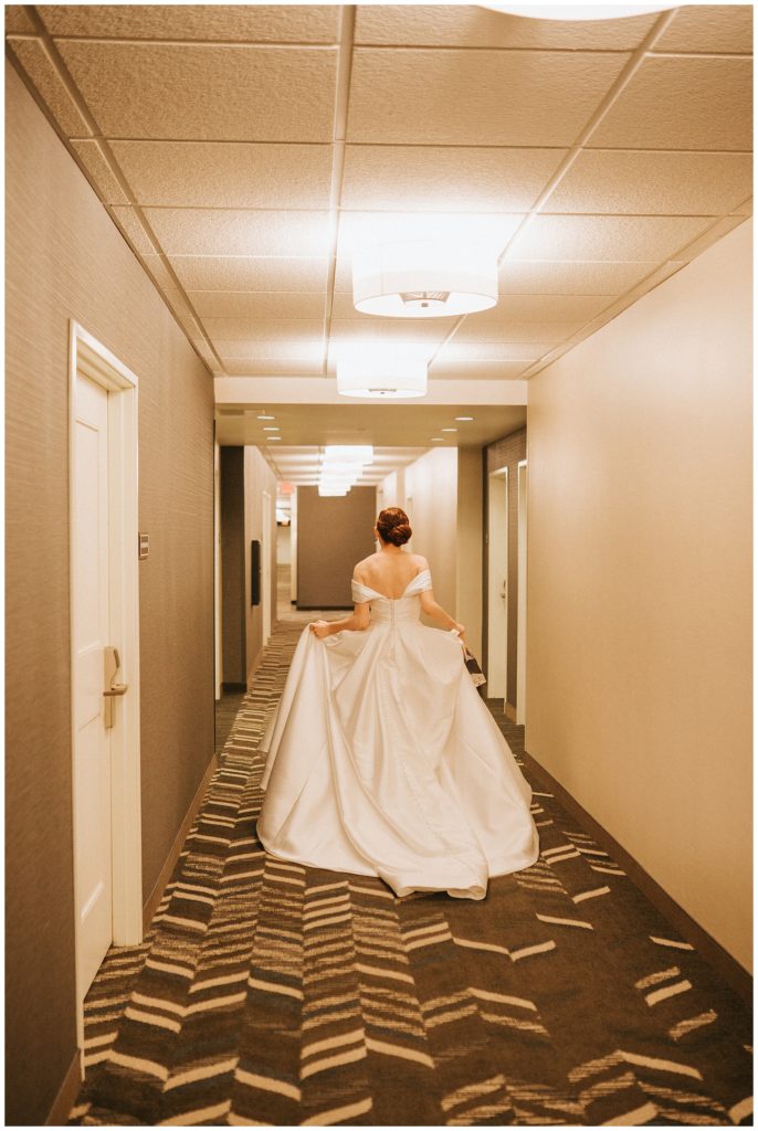 bride running down hallway with dress trailing behind her