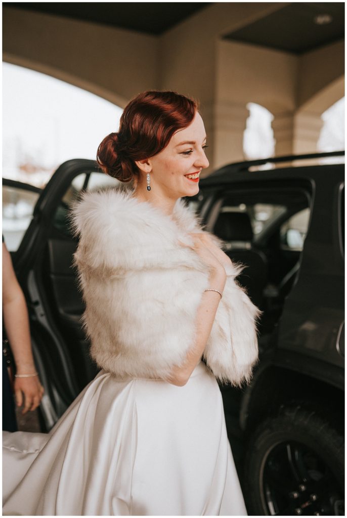 bride getting in the car to go to her wedding venue, wear white fur over her wedding dress