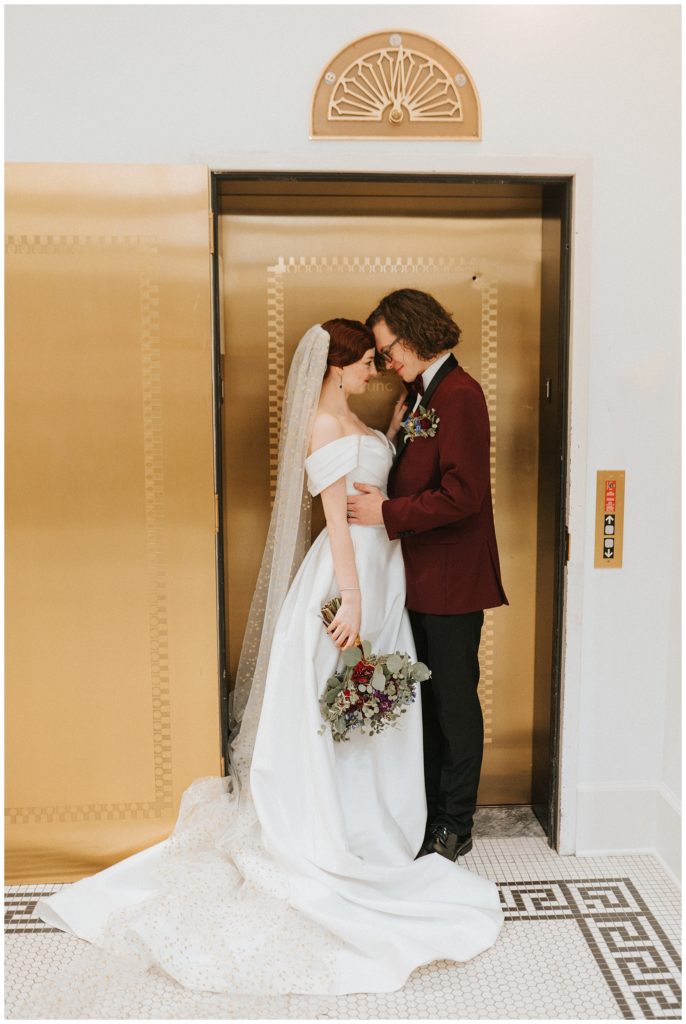 bride and groom cuddle in front of gold elevator at willard arts center